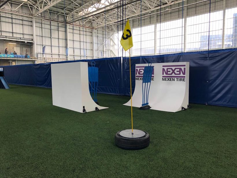 Two white half-pipe ramps with Nexen Tire banners and a hole flag