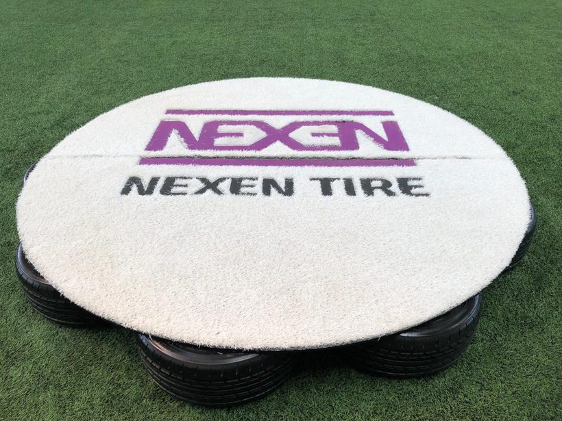 Nexen Tire branded tee pad mounted on a base of stacked tyres