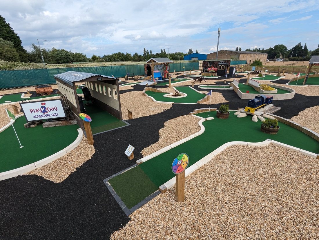 Wide daylight view of the finished eighteen hole course at Play2Day Wisbech, showing the carriage tunnel, greens and gravel paths